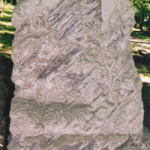 kamienna stela w formie nieregularnego kopca skalnego o chropowatej powierzchni i ukośnych nacięciach, z bryły kopca wyodrębniono krzyż łacińskich o gładkich ramionach, na steli motywy roślinne paproci ( u dołu, z lewej) i gałązki dębowej (pod krzyżem)