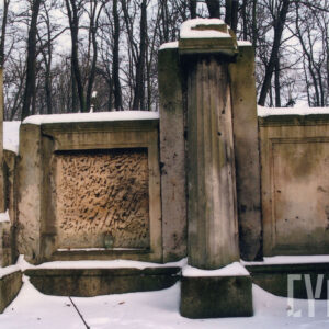 duży murowany, silnie uszkodzony nagrobek z wysokimi płycinami  i dorycką kolumną pośrodku w części zagłówkowej, nagrobek niesymetryczny, sceneria zimowa