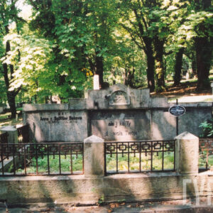 mogiła ziemna otoczona niskim murkiem z sześcioma czworobocznymi słupkami zwieńczonymi ostrosłupami połączonymi kutą kratą, w części zagłówkowej tablice inskrypcyjne w formie tryptyku, z prawej metalowy krzyż z owalną czarną tabliczką z białym napisem