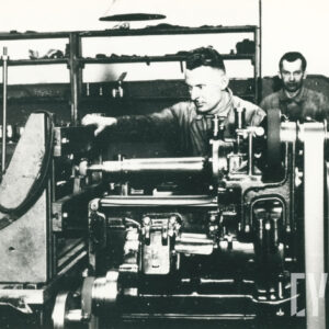 mężczyzna w średnim wieku w stroju roboczym, stojący przy dużym urządzeniu mechanicznym