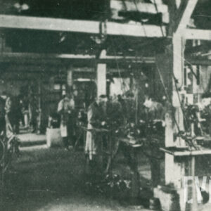 ludzie stojący przy urządzeniach mechanicznych, stojących w dużej hali