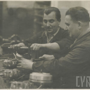 mężczyźni średnim wieku w ubraniach roboczych pracujący przy stanowisku ze sprzętem mechanicznym