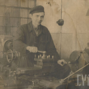 młody mężczyzna w stroju roboczym, stojący przy urządzeniu mechanicznym