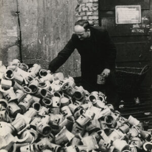 starszy mężczyzna przy stosie metalowych elementów silnikowych