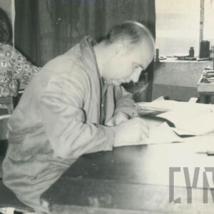 mężczyzna w średnim wieku w ubraniu roboczym, pracujący w gabinecie przy biurku