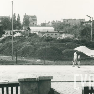 hałdy koksu leżące przed barakami, w oddali budynki mieszkalne