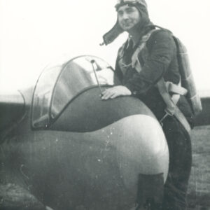 mężczyzna w stroju lotnika przy samolocie leżącym na trawiastym lądowisku