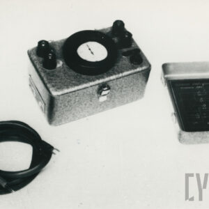 mała skrzynka w formie prostopadłościanu z tarczą zegarową, metalowym przykryciem i kablem elektrycznym