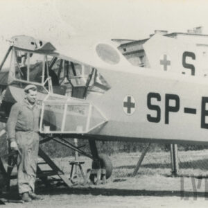 trzej mężczyźni przy samolocie, w głębi fragment budynku z cegieł