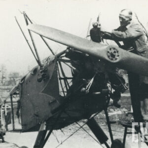 dwóch mężczyzn stojących przy samolocie, jeden z nich stoi na podwyższeniu i montuje części silnika