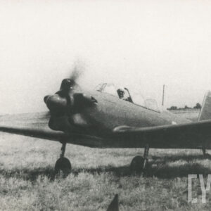 mężczyzna siedzący wewnątrz samolotu z uruchomionym silnikiem, stojącym na trawiastym lądowisku