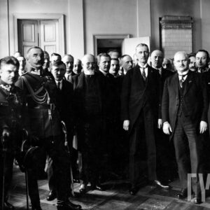 duża grupa mężczyzn, w tym wojskowi w mundurach z dystynkcjami, pozuje do fotografii, stojąc w kilku rzędach w pomieszczeniu, w głębi drzwi i piec kaflowy