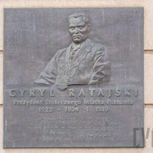 płaskorzeźbiona tablica z wizerunkiem popiersia mężczyzny i liternictwem przywieszona do ściany