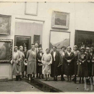 grupa kobiet stoi na tle licznych obrazów w ozdobnych ramach wiszących na ścianach