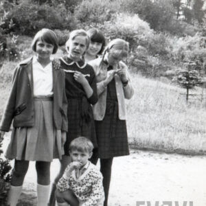 cztery dziewczynki stoją na tle zieleni, u dołu kuca mały chłopiec