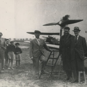 grupa osób pozująca do fotografii na tle samolotu ustawionego na pustej, trawiastej przestrzeni