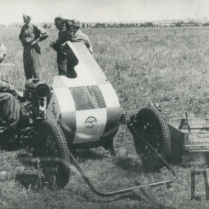 urządzenie mechaniczne na kołach obsługiwane przez mężczyzn w strojach roboczych, stojące na trawiastym lądowisku 