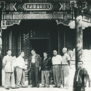 grupa mężczyzn pozująca do fotografii przed budynkiem wybudowanym w stylu tradycyjnej architektury chińskiej