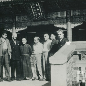 grupa mężczyzn pozująca do fotografii przed budynkiem wybudowanym w stylu tradycyjnej architektury chińskiej