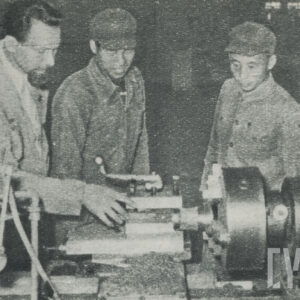 trzech mężczyzn w strojach roboczych stojących przy obrabiarce