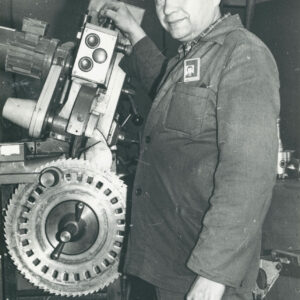 mężczyzna w średnim wieku w stroju roboczym, stojący przy urządzeniu mechanicznym