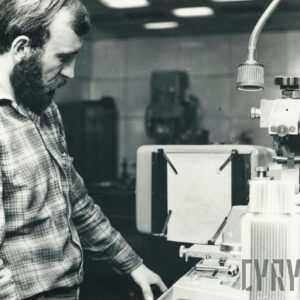 mężczyzna w średnim wieku w stroju roboczym obsługujący urządzenie mechaniczne