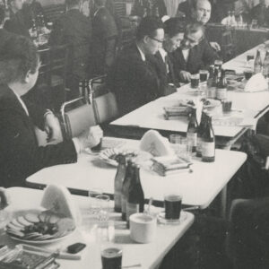 grupa mężczyzn siedzących przy stołach w czasie odczytu