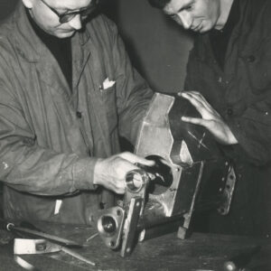 dwóch mężczyzn pracujących przy metalowym urządzeniu