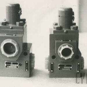 nieduże metalowe urządzenie w kształcie prostopadłościanu z śrubami i miejscami do montażu zaworów