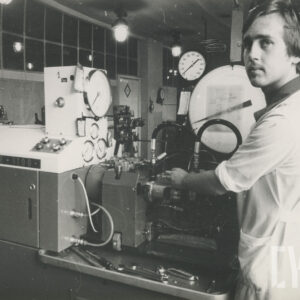 młody mężczyzna w stroju roboczym, stojący przy maszynie