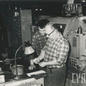 dwóch mężczyzn w strojach roboczych stojących nad biurkiem