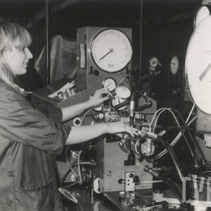 kobieta w stroju roboczym stojąca przy urządzeniach mechanicznych