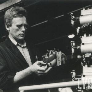 mężczyzna w stroju roboczym stojący przy urządzeniach mechanicznych