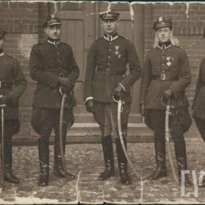 grupa stojących w szeregu pięciu mężczyzn w mundurach i czapkach na głowach, trzymających szable w dłoniach