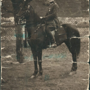 mężczyzna w mundurze siedzący na koniu, na tle ceglanego budynku