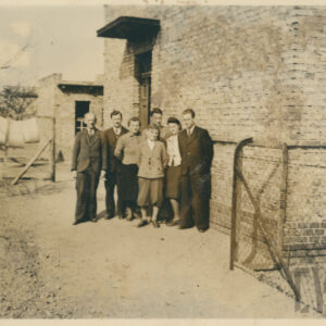 grupa osób pozująca do fotografii na tle nieotynkowanego domu z cegieł