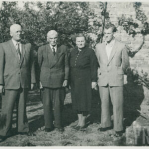 grupa osób pozujących do fotografii na tle budynku z cegieł