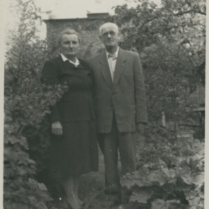 mężczyzna i kobieta w średnim wieku pozujący do fotografii na tle drzew i krzewów, w głębi fragment budynku z cegieł