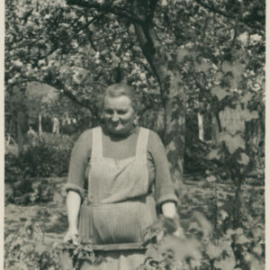 kobieta w średnim wieku w ubraniu roboczym pozująca do fotografii na tle drzew i krzewów