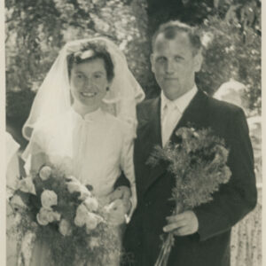 mężczyzna w garniturze z kobietą w sukni ślubnej, trzymającą w ręku bukiet kwiatów