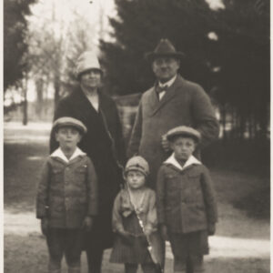 mężczyzna i kobieta w średnim wieku z dwójką młodych chłopców i małą dziewczynką, wszyscy ubrani w eleganckie płaszcze i nakrycia głowy, spacerująca po chodniku