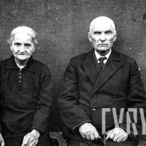 dwoje starszych ludzi, oboje z siwymi włosami, kobieta ubrana w suknię, a mężczyzna w garnitur i koszulę z krawatem