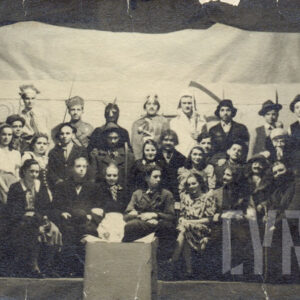 grupa młodych ludzi przebranych w różne stroje, część z nich trzyma w dłoniach rekwizyty, pozuje do fotografii na tle prowizorycznej scenografii