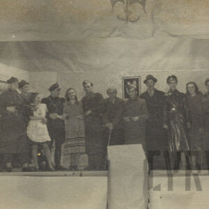 grupa młodych ludzi przebranych w różne stroje, pozujących do fotografii na tle prowizorycznej scenografii