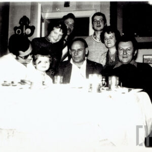 grupa osób w różnym wieku, siedząca przy nakrytym stole wewnątrz mieszkania