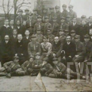 grupa chłopców w mundurach harcerskich oraz mężczyzn w garniturach pozująca do fotografii na tle pomnika