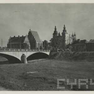 most nad suchym kanałem rzeki, w głębi z lewej dwa budynki ze spadzistymi dachami, z prawej kościół z dwiema wieżami