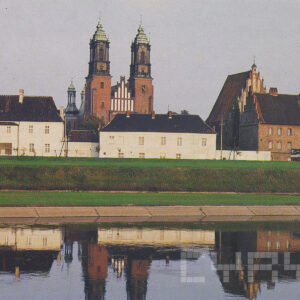 na pierwszym planie rzeka, w głębi niskie budynki ze spadzistymi dachami, w głębi kościół z dwiema wieżami