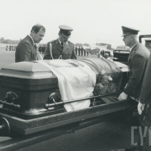 trumna nakryta biało-czerwoną flagą leży na lawecie, po obu jej stronach stoi trzech żołnierzy i mężczyzna w cywilu