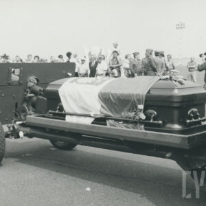 trumna nakryta biało-czerwoną flagą na lawecie, z lewej działo artyleryjskie, w głębi grupa ludzi